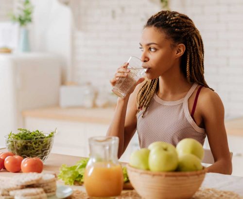 Woman drinking water in her kitchen