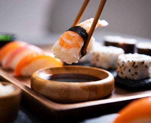 Nigiri on chopsticks with sushi in the background