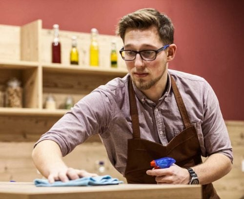 Man wiping surfaces in kitchen