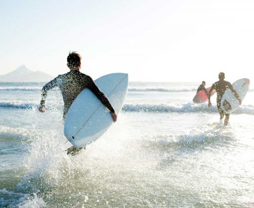 surfers running into the sea