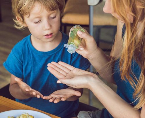mother applying hand sanitiser on son