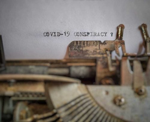 typewriter typing words on a page about COVID-19 conspiracies