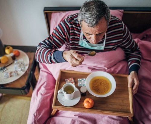 man with coronavirus at home eating soup