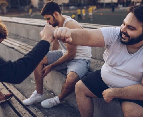 Man with obesity fist bumping friend
