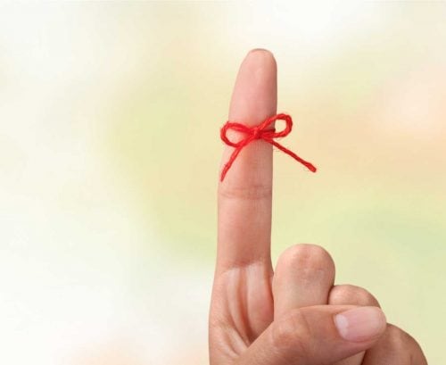 Finger with a red bow tied around it