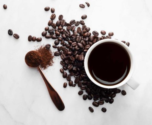 Cup of black coffee with coffee beans and coffee powder