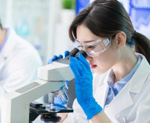 Woman scientist looking through microscope