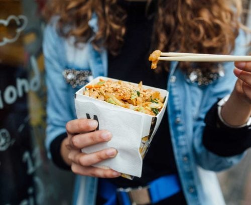 Woman eating takeaways with chopsticks from a box