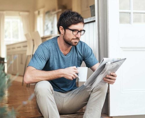 Man drinking coffee and reading a newspaper