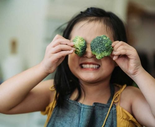 Young healthy girl with broccoli in her eyes