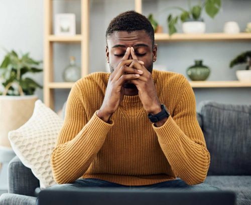Man sitting on couch looking stressed