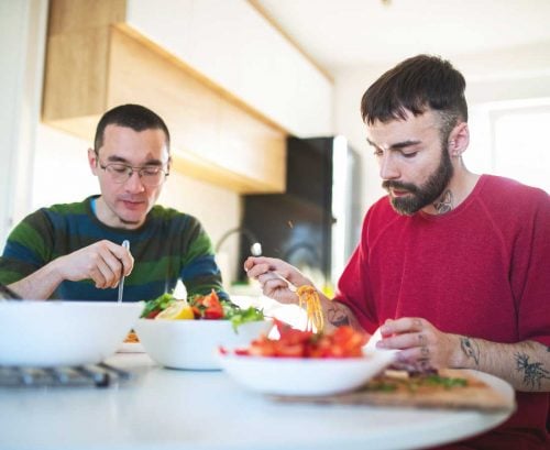 Two men eating lighter bolognese