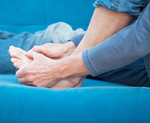 Person with gout holding their sore foot