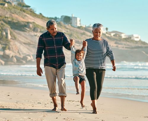 Older couple swinging their grandchild while walking along the beach