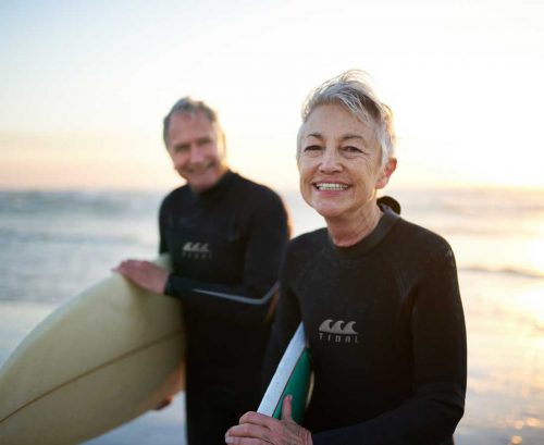 Healthy older couple with surfboards