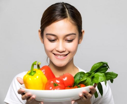 Teenage girl smiling at a plate of vegetables