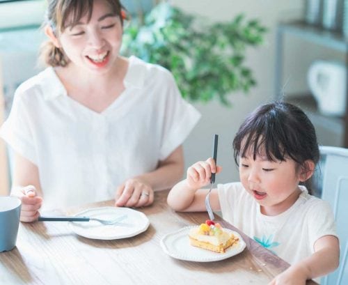 Mother and daughter at the table. Daughter eating a dessert