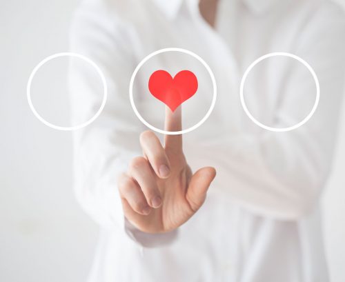 person touching a heart graphic on a perspex screen