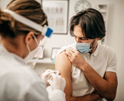 Man with mask on getting a COVID vaccination