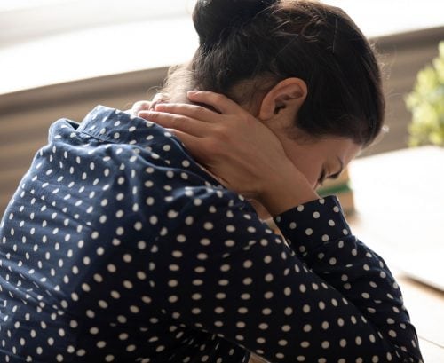 Woman leaning over desk in pain