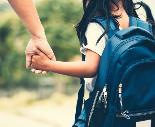 Primary school child walking to school holding mother's hand