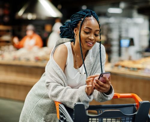 Woman using her smartphone at the supermarket