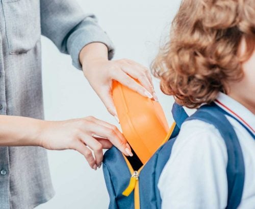 Mother putting lunchbox into child's bag