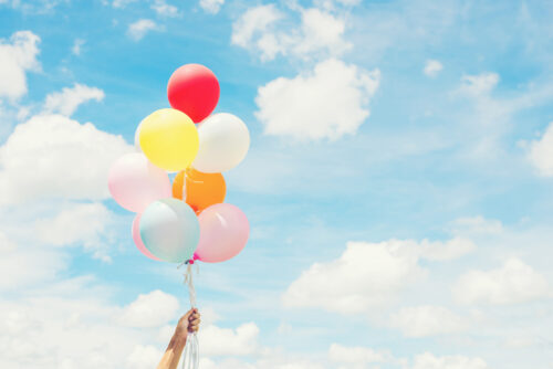 An image of a hand holding a bunch of balloons
